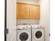 Bright laundry room with side-by-side white washer and dryer and wood cabinets at 238 Cherrytree Dr, Fort Mill, SC 29715