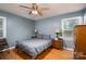Calm blue bedroom featuring hardwood floors, ceiling fan, and plenty of natural light at 2418 Live Oak Ct, Gastonia, NC 28056