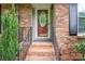Close-up of the front door entrance featuring brick steps and iron railings, framed by manicured greenery at 2418 Live Oak Ct, Gastonia, NC 28056