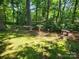 Lush backyard with mature trees, a bird bath, benches, and manicured lawn at 2461 Ridgecrest Dr, Stanley, NC 28164