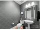 Stylish half-bathroom featuring designer wallpaper, a pedestal sink, and a modern mirror at 400 N Church St # 422, Charlotte, NC 28202