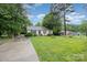Inviting single-story home with a lush green lawn, mature trees, and a long driveway leading to the residence at 401 Yadkin St, Granite Quarry, NC 28072
