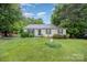 Well-kept single-story home featuring lush greenery, a manicured lawn, and a charming garden with a decorative statue at 401 Yadkin St, Granite Quarry, NC 28072