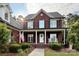 Beautiful two-story brick home with a well-manicured lawn, American flag, and a charming front porch with rocking chairs at 4230 Berry Hill Ct, Concord, NC 28025