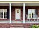 Inviting front porch with brick base, white columns, rocking chairs, and a decorated front door at 4230 Berry Hill Ct, Concord, NC 28025