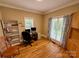 Bright home office featuring hardwood floors, a built-in cabinet, a desk with monitors, and ample natural light from a window at 4230 Berry Hill Ct, Concord, NC 28025