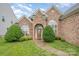 Elegant brick home featuring arched windows, manicured bushes, and a stylish front door entrance at 5052 Ashley Pl, Bessemer City, NC 28016