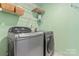 Modern laundry room with shelving features sleek, front-loading washer and dryer at 5233 Fairvista Dr, Charlotte, NC 28269