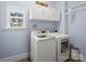 Bright laundry room features a washer and dryer, with white cabinets and a view of nature from the window at 538 Fairwoods Dr, Huntersville, NC 28078