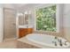 Bright bathroom with a large window, soaking tub, and a tiled shower with glass door at 6655 Maple Spring Ct, Denver, NC 28037