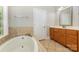 Bright bathroom features a soaking tub with tile surround and vanity with wooden cabinets at 6655 Maple Spring Ct, Denver, NC 28037