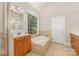 This bathroom features a jacuzzi tub and single vanities with warm wood cabinets at 6655 Maple Spring Ct, Denver, NC 28037