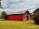 Classic red barn on a lush green field under a cloudy sky, surrounded by trees at 6714 Old Shelby Rd, Vale, NC 28168