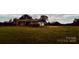 Sprawling front lawn with a charming ranch-style home and barn in the background, offering a tranquil country setting at 6714 Old Shelby Rd, Vale, NC 28168