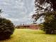 A sprawling brick home with a large green lawn, nestled among mature trees under a dramatic sky at 6714 Old Shelby Rd, Vale, NC 28168