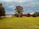 Expansive green field featuring a red barn and a white storage shed in a rural setting at 6714 Old Shelby Rd, Vale, NC 28168