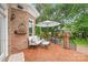 Cozy brick back patio with white cushioned seating, black iron railings and a large umbrella for shade at 7018 Dowington Dr, Charlotte, NC 28277