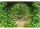 Lush backyard garden with stone bench and flower arrangements beneath a leafy archway at 7018 Dowington Dr, Charlotte, NC 28277