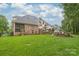 Expansive backyard with a well-manicured lawn, patio, outdoor kitchen, and mature trees providing ample shade at 7018 Dowington Dr, Charlotte, NC 28277