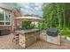 Stone outdoor kitchen with a built-in grill, bar seating, and stainless steel storage for outdoor entertaining at 7018 Dowington Dr, Charlotte, NC 28277