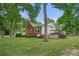 Quaint brick home with well-maintained lawn, mature trees, and a large wooden deck at 725 W Graham St, Shelby, NC 28150