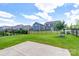Large backyard featuring lush green grass, a concrete patio, a black metal fence, and views of nearby homes at 1004 Earlston Rd, Indian Trail, NC 28079
