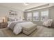 Well-lit bedroom with a tray ceiling, a bed with a cushioned bench, and a cozy reading corner at 1020 Bannister Rd, Waxhaw, NC 28173