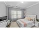 This bedroom features a modern design, light gray walls, a large window, and a white bed frame for a bright, airy feel at 11209 Flenniken Ct, Charlotte, NC 28277