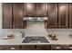 Gourmet kitchen featuring a modern range, backsplash, granite countertops, and dark wood cabinets for a sophisticated cooking space at 11209 Flenniken Ct, Charlotte, NC 28277