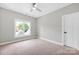 Bright bedroom featuring neutral walls, plush carpet, a large window, and a white paneled door at 12711 Duncourtney Ln, Charlotte, NC 28277