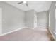 Neutral bedroom with a large window, plush carpet, ceiling fan, and a white paneled door at 12711 Duncourtney Ln, Charlotte, NC 28277