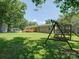 A lush backyard with a brick home, wooden deck, and a swing set at 1306 Abbey Ct, Lancaster, SC 29720
