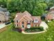 Well-manicured lawn and landscaping surround this two-story brick home with mature trees at 15737 Agincourt Dr, Huntersville, NC 28078