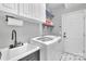 Well-equipped laundry room with modern washer and dryer, sink, and storage shelving at 15737 Agincourt Dr, Huntersville, NC 28078