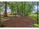 Backyard playground features a swing set, slide, and playhouse nestled among mature trees and a fenced yard at 15737 Agincourt Dr, Huntersville, NC 28078