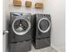 Modern laundry room with gray front-load washer and dryer, plus convenient overhead shelving for storage at 1659 Loggerhead Dr, Lancaster, SC 29720