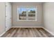 A bright bedroom featuring new vinyl floor, white trim, and a window showing greenery outside at 2009 Auten Rd, Gastonia, NC 28054