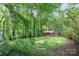 Lush backyard view of a brick home with a wooden deck, surrounded by mature trees and greenery at 205 E Cleveland Ave, Bessemer City, NC 28016