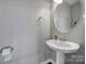 Convenient powder room featuring a pedestal sink, round mirror, and neutral wall color at 3342 Yarmouth Ln, Gastonia, NC 28056