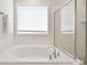 Bathroom with a large white tub and shower with glass door at 3924 Dahlia Dr, Harrisburg, NC 28075