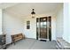 Inviting front porch featuring a dark wood door, bench seating, and elegant light fixtures at 3924 Dahlia Dr, Harrisburg, NC 28075