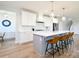 Well-lit kitchen showcasing a center island with seating, white cabinets, stainless appliances, and hardwood floors at 3924 Dahlia Dr, Harrisburg, NC 28075