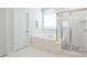 Elegant bathroom with soaking tub, separate glass-enclosed shower, and stylish white tiling at 3924 Dahlia Dr, Harrisburg, NC 28075