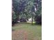 Lush backyard featuring green grass, mature trees, and parked car near a charming home at 5023 Dogwood Ln, Stanley, NC 28164
