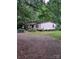 Charming single-story home with mature trees, a gravel driveway, and a covered front porch at 5023 Dogwood Ln, Stanley, NC 28164