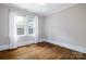 Bedroom featuring gleaming hardwood floors and large windows dressed with white curtains at 524 Hawthorne Ln, Charlotte, NC 28204