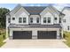 Modern home featuring white siding, a dark roof, black garage doors, and stone accents at 6032 Corbin Woods Ct, Charlotte, NC 28226