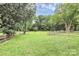 Expansive green backyard enclosed with a wooden fence and mature trees providing shade and privacy at 6908 Lancer Dr, Charlotte, NC 28226