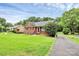 Charming brick home with a manicured front lawn, complemented by a red front door and mature trees at 6908 Lancer Dr, Charlotte, NC 28226
