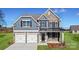 Beautiful two-story home boasts a stone and blue shingle exterior, attached two-car garage, and manicured lawn at 7101 Butternut Oak Ter, Huntersville, NC 28078